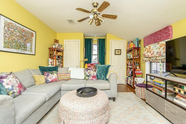 living area with vaulted ceiling, wood finished floors, visible vents, and a ceiling fan