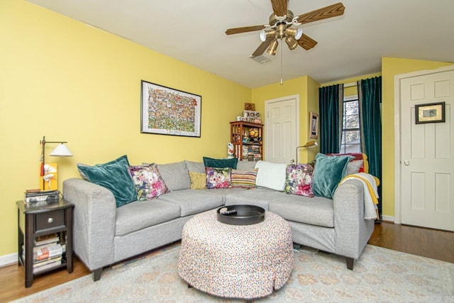 living area featuring visible vents, ceiling fan, baseboards, and wood finished floors