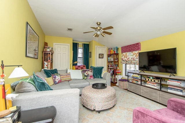 living area with vaulted ceiling, a healthy amount of sunlight, visible vents, and ceiling fan