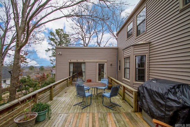 wooden terrace with outdoor dining area and a grill