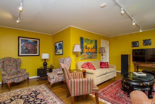 living room with baseboards, track lighting, ornamental molding, and wood finished floors