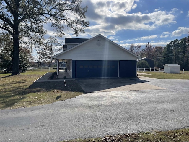 view of side of property featuring an outbuilding, a yard, fence, and driveway