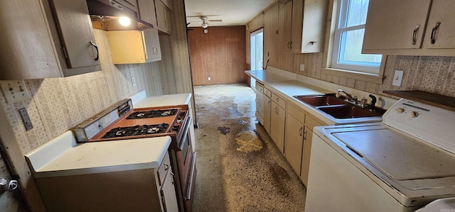 kitchen featuring washer / clothes dryer, stainless steel gas range, light countertops, under cabinet range hood, and a sink