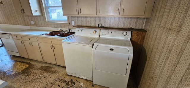 clothes washing area with washer and clothes dryer, a sink, cabinet space, and wallpapered walls