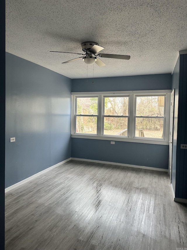 empty room featuring a ceiling fan, a textured ceiling, baseboards, and wood finished floors