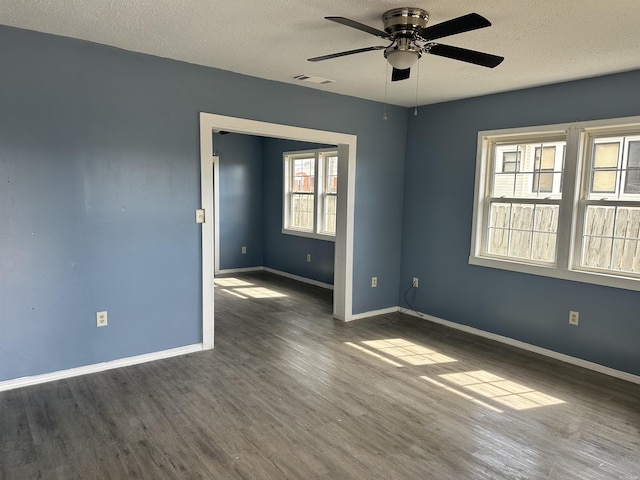 spare room with baseboards, a textured ceiling, visible vents, and wood finished floors