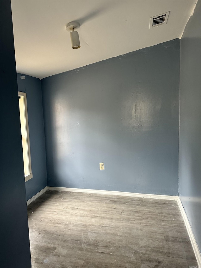 empty room featuring baseboards, visible vents, and wood finished floors