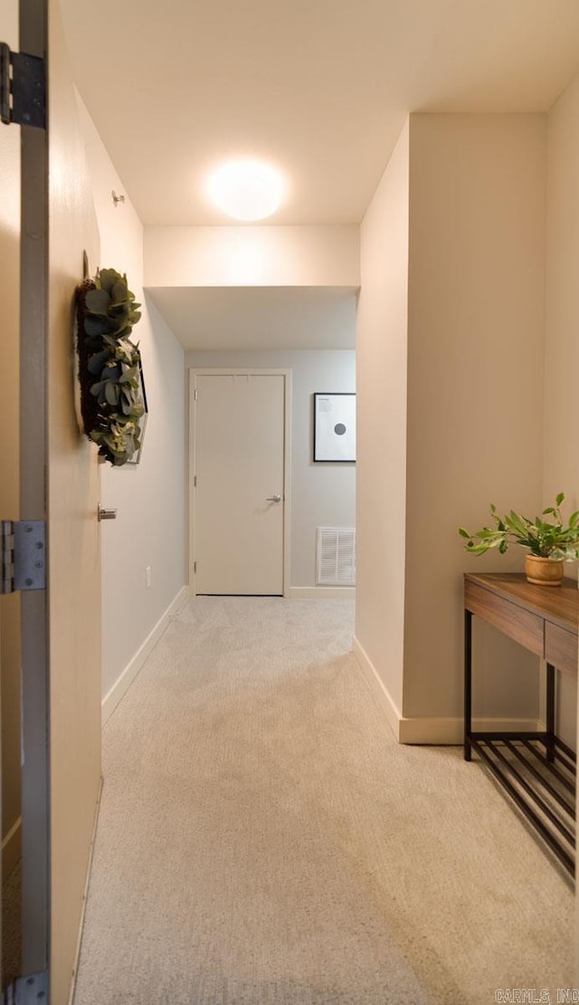 hallway featuring visible vents, baseboards, and carpet flooring