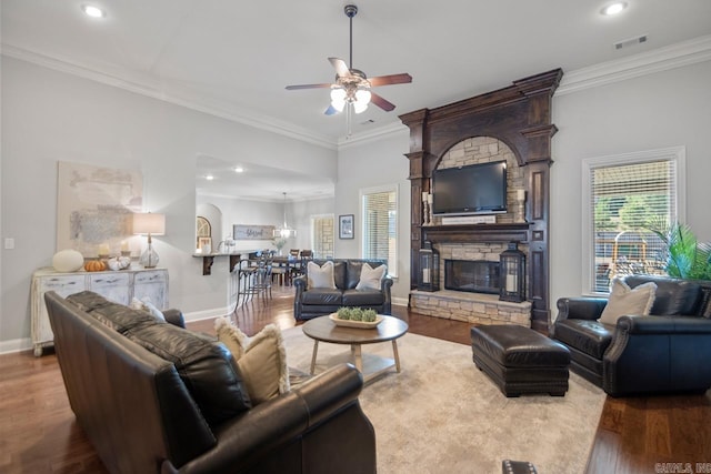 living area with baseboards, visible vents, ornamental molding, wood finished floors, and a fireplace