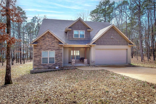 view of front of property featuring a garage, concrete driveway, stone siding, roof with shingles, and a porch