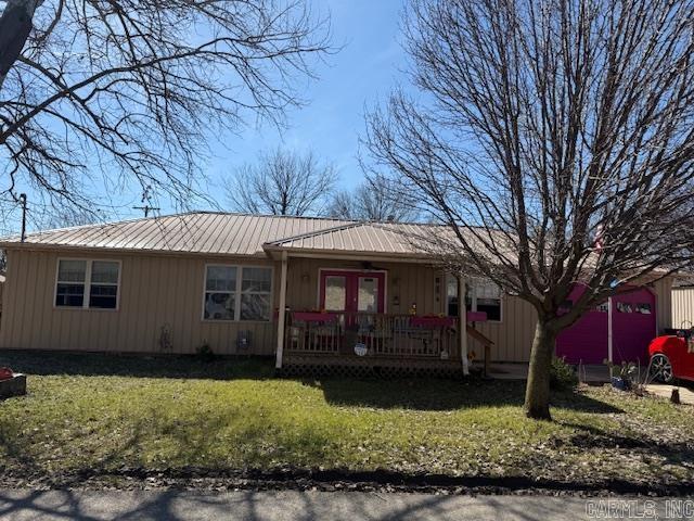 single story home with a porch, french doors, an attached garage, a front yard, and metal roof