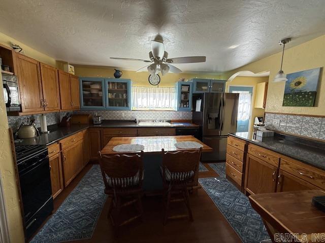 kitchen featuring fridge with ice dispenser, range, glass insert cabinets, and brown cabinets