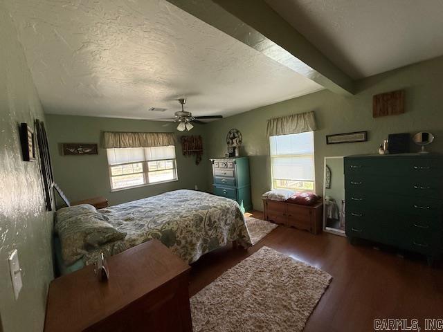 bedroom with visible vents, multiple windows, a textured ceiling, and dark wood-style flooring