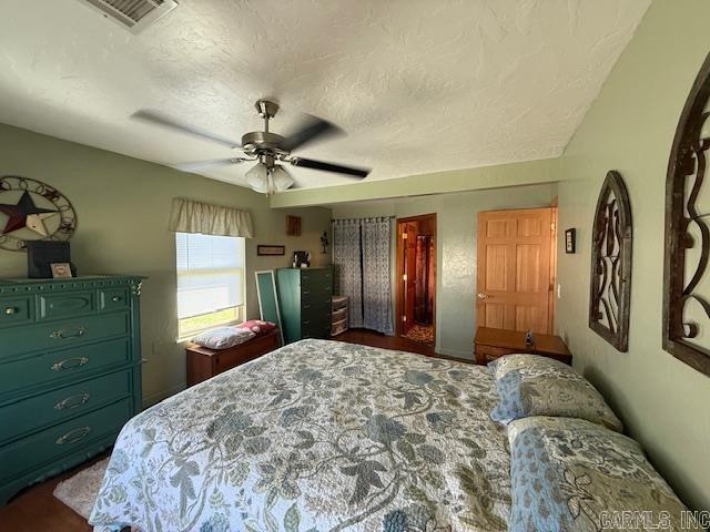 bedroom featuring ceiling fan, visible vents, and a textured ceiling