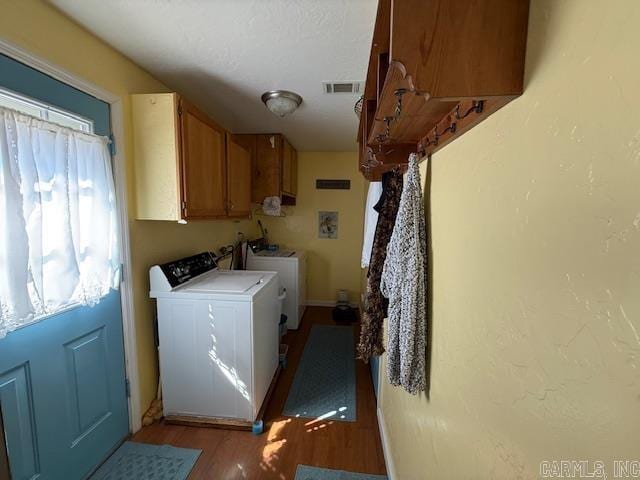 laundry area with washing machine and dryer, cabinet space, light wood-type flooring, and visible vents