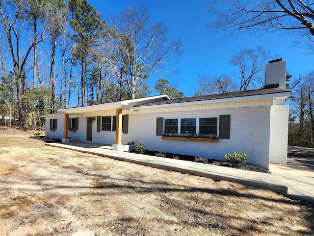 single story home featuring a chimney and brick siding