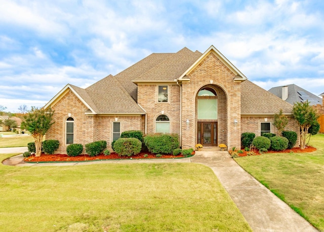 traditional-style house featuring brick siding, a shingled roof, and a front yard