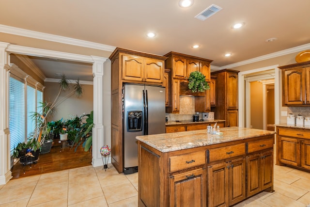 kitchen with light tile patterned floors, visible vents, a center island, stainless steel fridge, and ornate columns