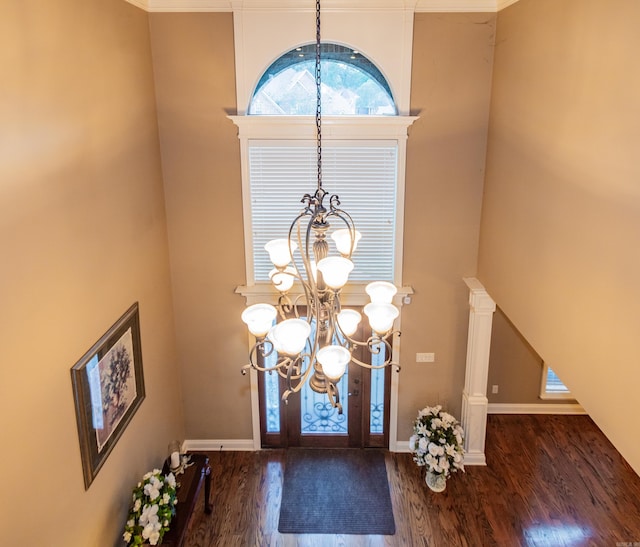 foyer entrance featuring wood finished floors, decorative columns, baseboards, and an inviting chandelier