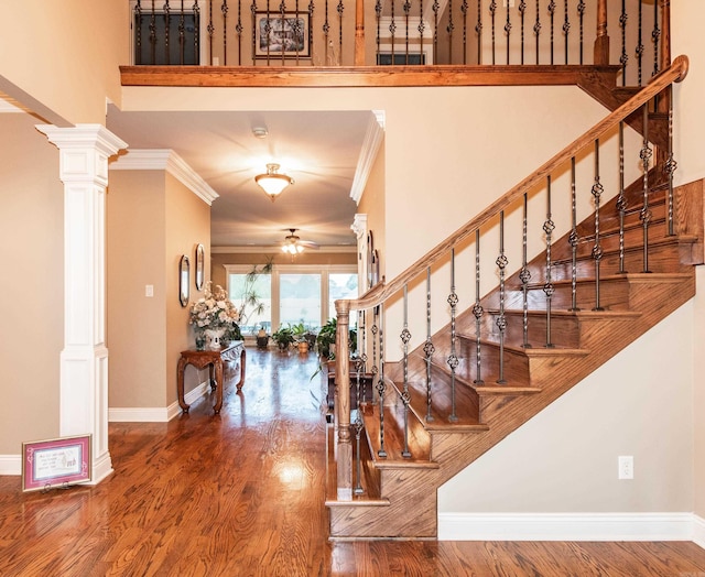 entryway with ornamental molding, stairway, wood finished floors, and decorative columns