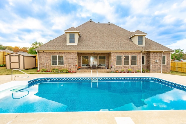 view of swimming pool featuring an outdoor structure, fence, a fenced in pool, a storage unit, and a patio area