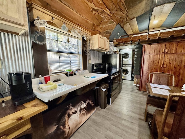 kitchen with stacked washer and clothes dryer, black electric range, wood walls, and light wood finished floors