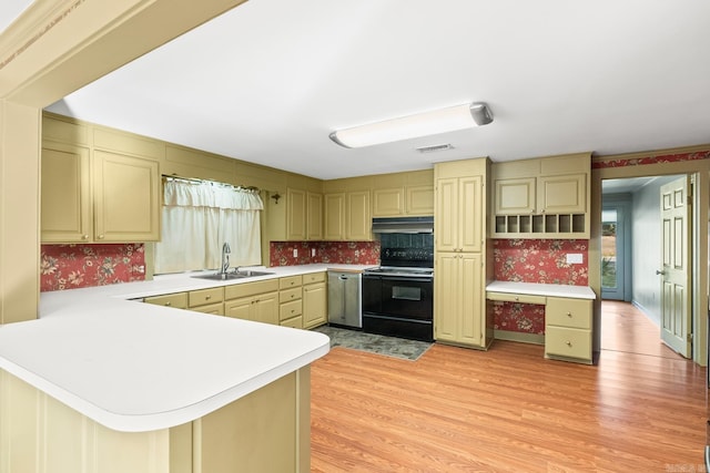 kitchen with wallpapered walls, black electric range oven, light countertops, and a sink