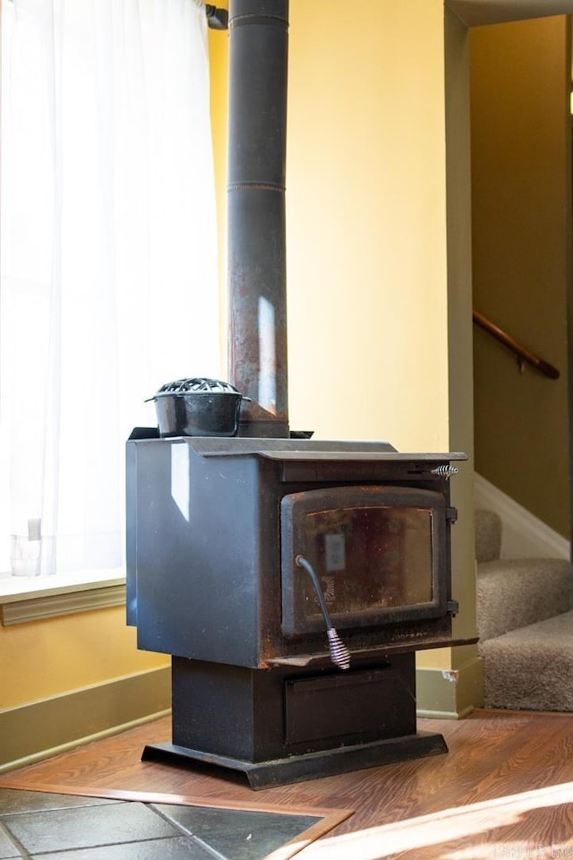 room details featuring wood finished floors, a wood stove, and baseboards