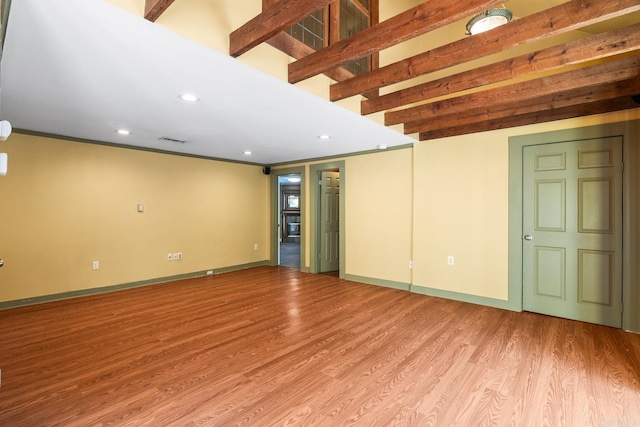 unfurnished living room with beam ceiling, wood finished floors, and visible vents