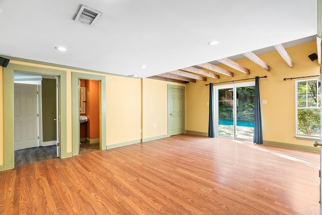 spare room featuring light wood-style floors, visible vents, beam ceiling, and recessed lighting