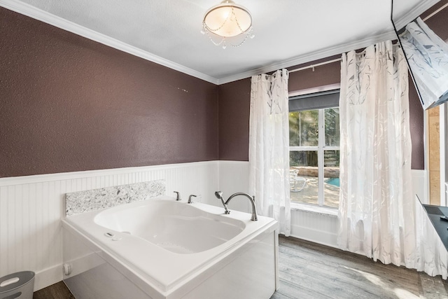 full bathroom featuring wainscoting, wood finished floors, a bath, and crown molding