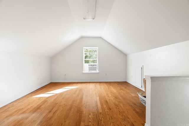 bonus room with light wood finished floors, baseboards, vaulted ceiling, and cooling unit