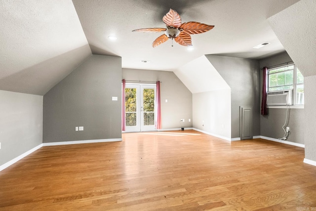 additional living space with a textured ceiling, lofted ceiling, light wood-style flooring, and baseboards