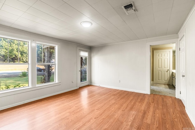 empty room featuring light wood finished floors, visible vents, and baseboards