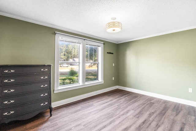 interior space with a textured ceiling, baseboards, crown molding, and wood finished floors