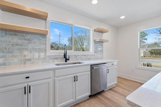 kitchen featuring tasteful backsplash, stainless steel dishwasher, light wood-style floors, open shelves, and a sink