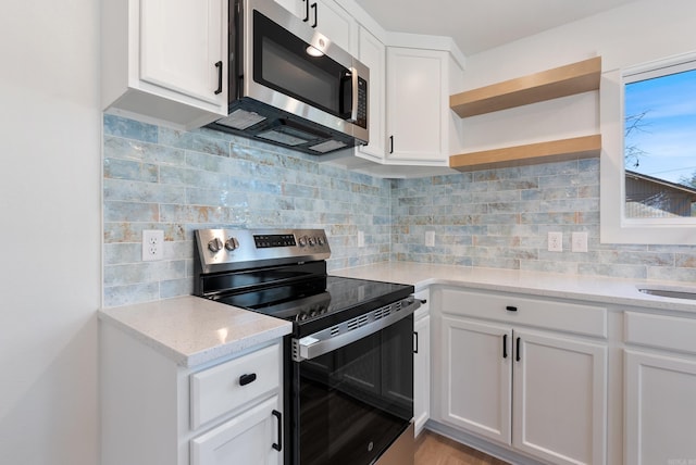 kitchen featuring stainless steel appliances, white cabinetry, decorative backsplash, light stone countertops, and open shelves