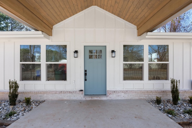 entrance to property with board and batten siding and a patio area