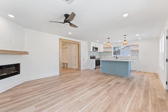 kitchen featuring open shelves, stainless steel appliances, light countertops, backsplash, and a glass covered fireplace