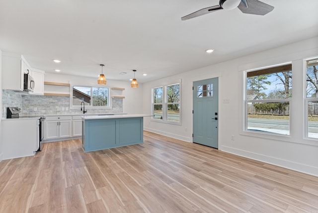 kitchen with open shelves, stainless steel appliances, tasteful backsplash, light countertops, and light wood-style floors