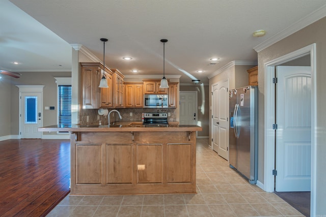 kitchen featuring crown molding, backsplash, appliances with stainless steel finishes, a sink, and a peninsula