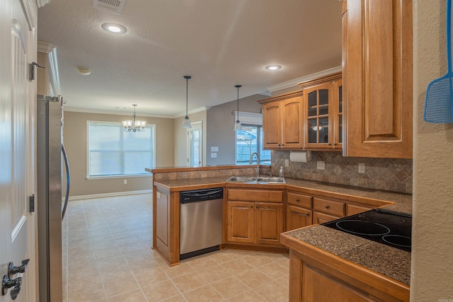 kitchen featuring a peninsula, a sink, appliances with stainless steel finishes, tile counters, and brown cabinetry