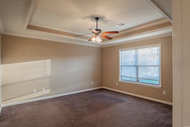 unfurnished room with visible vents, baseboards, dark colored carpet, a tray ceiling, and crown molding