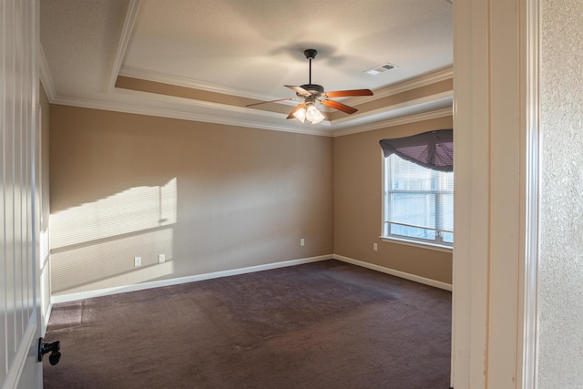 unfurnished room with dark carpet, a raised ceiling, visible vents, and crown molding