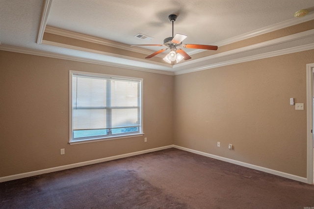 unfurnished room with baseboards, visible vents, a raised ceiling, ornamental molding, and dark colored carpet