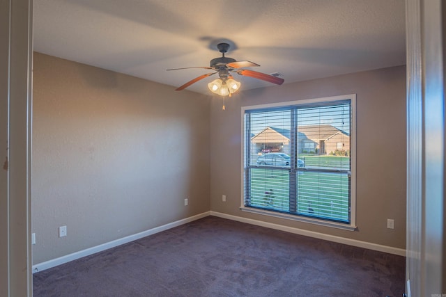 spare room with a ceiling fan, visible vents, dark carpet, and baseboards