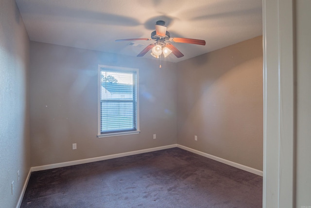 empty room featuring ceiling fan, dark carpet, and baseboards