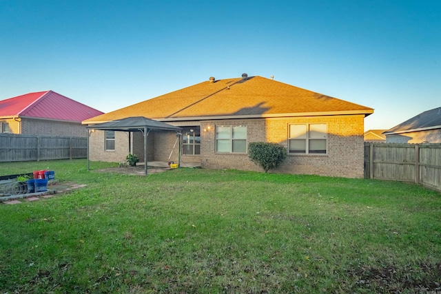 rear view of house with brick siding, a lawn, a gazebo, a patio area, and a fenced backyard