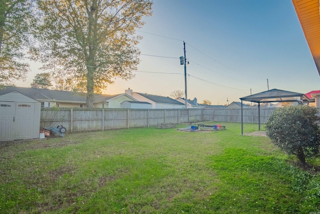 view of yard featuring a storage shed, an outdoor structure, and a fenced backyard