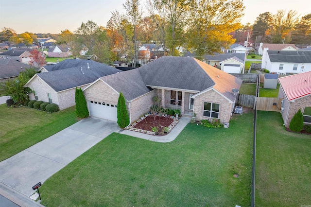 view of front of house with driveway, an attached garage, fence, and a yard